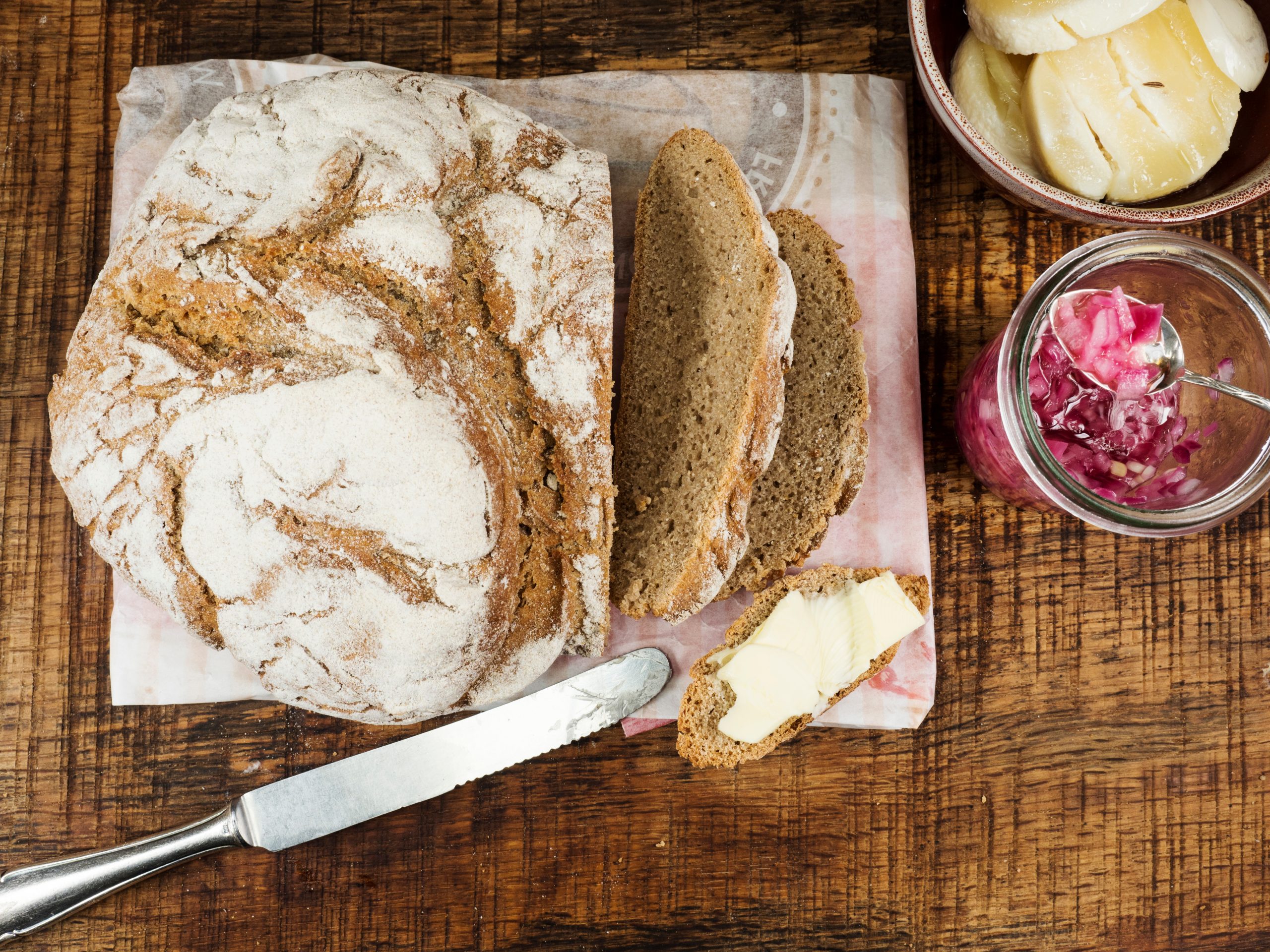 Frisches Brot und herzhafte Beilagen auf einem rustikalen Holztisch